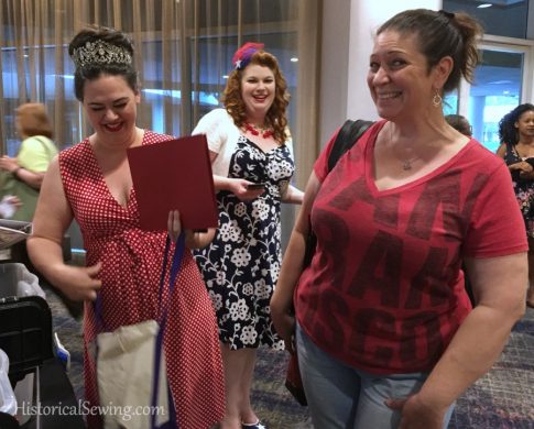 Taylor of Dames a la Mode, Jenny-Rose, and Diana of Renaissance Fabrics picking up their student/teacher packets on Thursday night of Costume College 2018.
